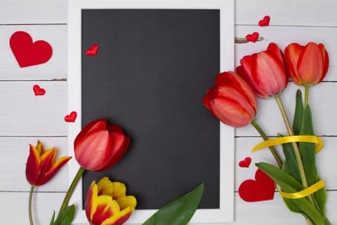 Empty clean black chalkboard with red tulips and hearts. Top view Stock Photos