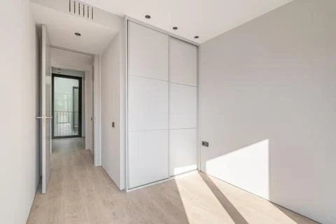 Empty clean bright bedroom with light wooden parquet and white wardrobe with 스톡 사진