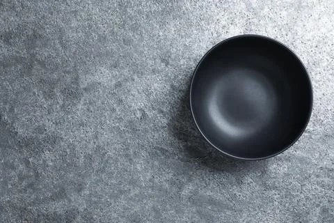 Empty clean ceramic bowl on grey table, top view. Space for text Stock Photos