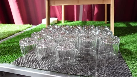 Empty clean drinking glasses arranged on a table for an outdoor event catering Stock Footage 331666164