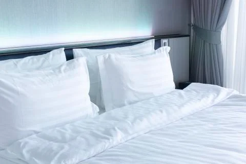 Empty clear bedroom with white bed and pillows on the bed. Stock Photos