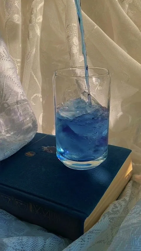 Empty clear glass on a blue book with soft aesthetic fabric background Video stock 344231810