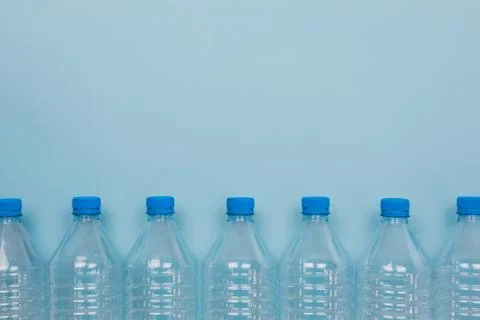 Empty clear plastic bottles with caps stacked on a blue background. Recycling Stock Photos