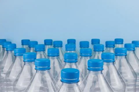 Empty clear plastic bottles with caps stacked on a blue background. Recycling Foto stock