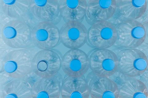 Empty clear plastic bottles with caps stacked on a blue background. Recycling Stock Photos