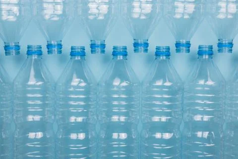 Empty clear plastic bottles without caps stacked on a blue background. Recycl Foto stock