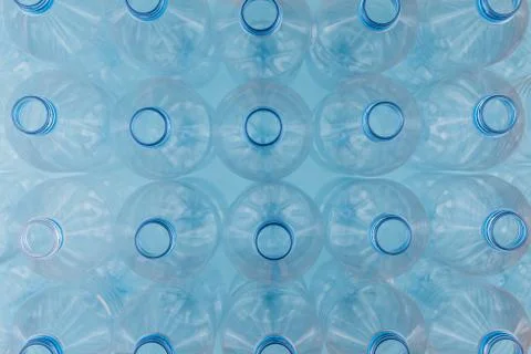 Empty clear plastic bottles without caps stacked on a blue background. Recycl Stock Photos