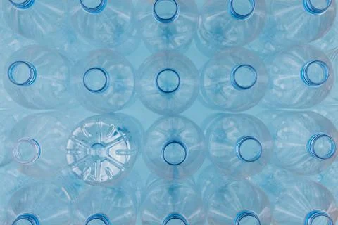 Empty clear plastic bottles without caps stacked on a blue background. Recycl Stock Photos