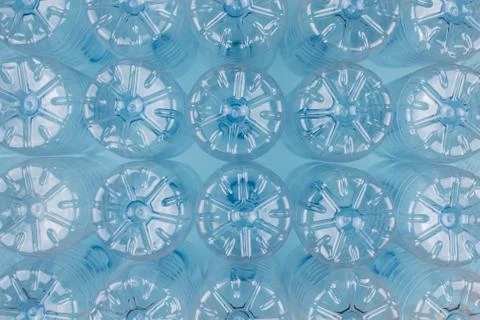 Empty clear plastic bottles without caps stacked on a blue background. Recycl Stock Photos