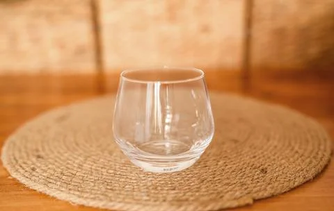 Empty clear water glass on a round coaster on a wooden table Stock Photos