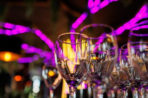 Empty clear wineglasses stand in rows on bar counter at nightclub, blurred pu Stock Photos