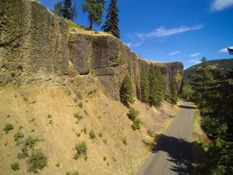 Empty cliff road running through mountains with pine trees growing on steep r Stock Photos