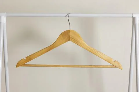 Empty clothes hangers on a wardrobe rack on a colored background. Stock Photos