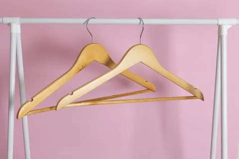 Empty clothes hangers on a wardrobe rack on a colored background. Stock Photos