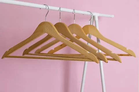 Empty clothes hangers on a wardrobe rack on a colored background. Stock Photos