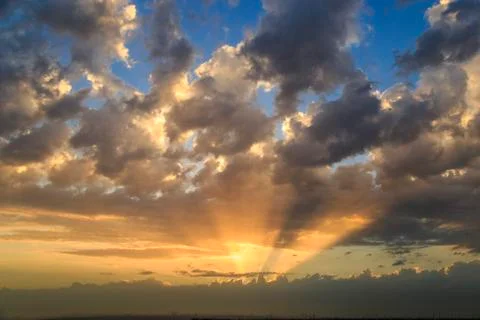 Empty cloudy sky from orange to blue with sun rays during the sunset Stock-Fotos