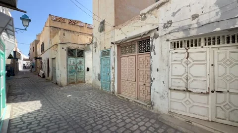 Empty cobbled alley lined with weathered pastel doors and plaster walls under Stock Footage 340959333