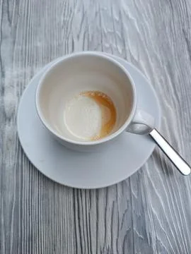 Empty coffee cup after drink on coffee restaurant grey table with tea spoon Stock Photos