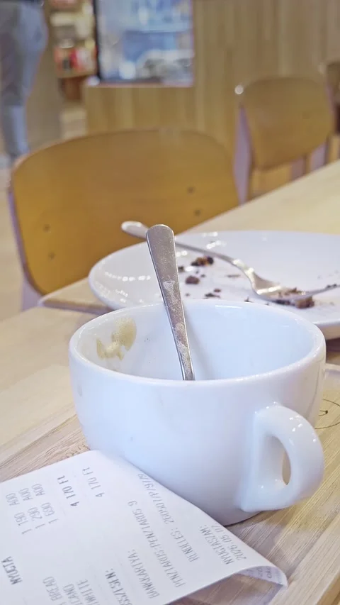 Empty Coffee Cup and Bill Receipt on Cafe Table After City Dining Stock Footage 345226357