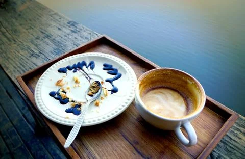 Empty coffee cup and white plate with crumbles of eaten cake and used spoon.. Stock Photos