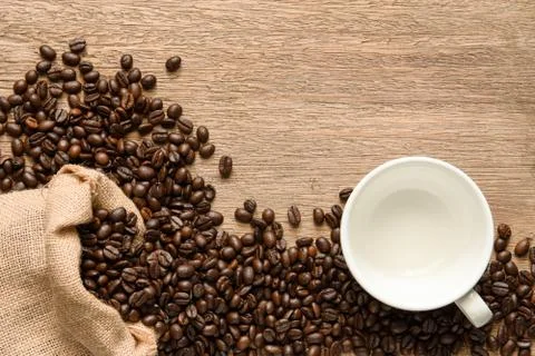 Empty coffee cup with beans and hemp sack bag on wood table, top view. Foto stock