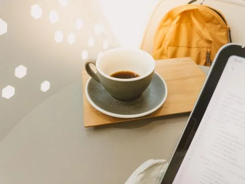 Empty Coffee Cup on Table Next to Digital Tablet and Backpack in Cafe Setting Stock Photos