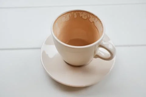 Empty coffee cup on a white table after drinking. Minimal lifestyle scene sym Stock Photos