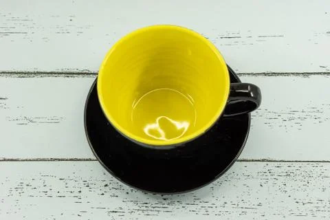 An empty coffee or tea cup yellow color inside on white wooden background. Stock Photos