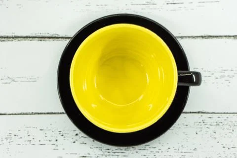 An empty coffee or tea cup yellow color inside on white wooden background. Stock Photos