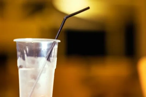 Empty Cold Clear Plastic Glass With Black Cocktail Straw in Hotel Restaurant. Stock Photos