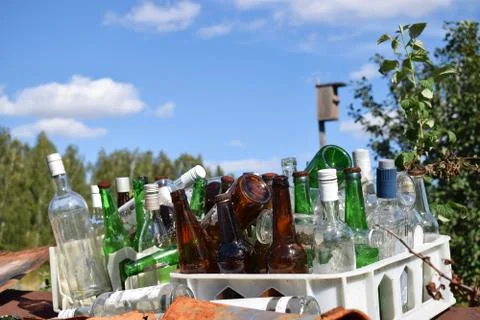 Empty colored bottles in box with sky background Stock Photos