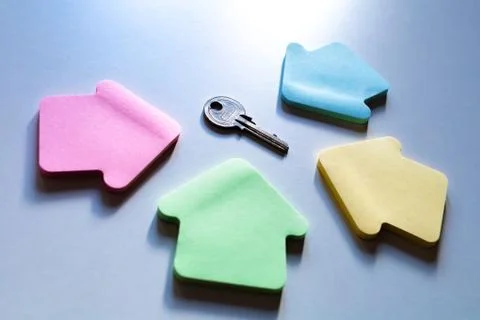 Empty colorful house frames on blue background with metal key. Stock Photos