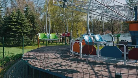 Empty Colorful Swing Carousel Ride Sitting Idle in Quiet Sunny Park 動画素材 334125628