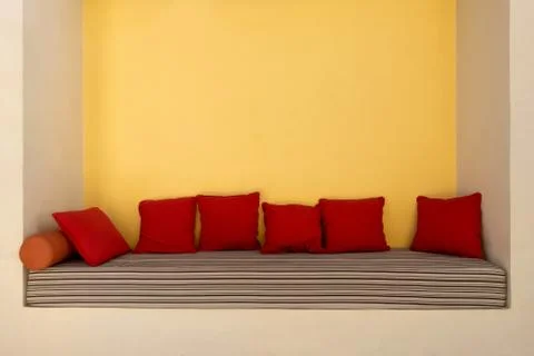 Empty comfortable niche couch with striped mattress and red pillows Stock Photos