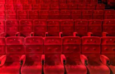 Empty comfortable red seats with numbers in the hall of the cinema or theater Stock Photos