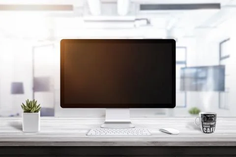 Empty computer display on office desk for mockup. Plant and coffee mug beside Stock Photos