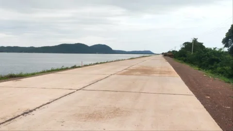 Empty Concrete Road Perspective Along Reservoir with Mountain View Stock Footage 343774780