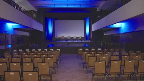 Empty conference room with empty chairs on stage - sow motion dolly shot. Stock Footage 256743880