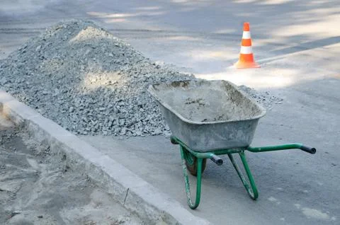 An empty construction cart on the sidewalk. It stands at a pile of rubble. Stock Photos