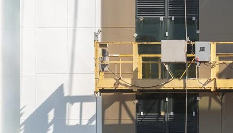 An empty construction winch hanging from cables on the facade of a building Stock Photos