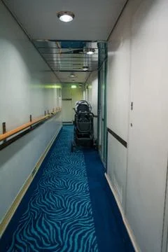 Empty corridor of a ship with a stroller outside a cabin Stock Photos