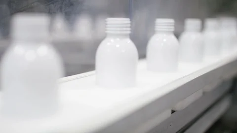 Empty cosmetic bottles being placed on conveyor belt on production line Stock Footage 107954439