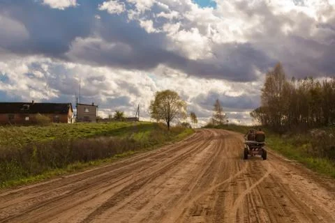 An empty country road in Belarus in a cloudy sunny day with a man in horse cart. Foto stock