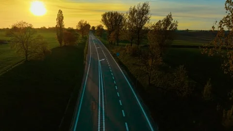 Empty countryside road winding through open fields at sunset. Asphalt route Stock Footage 316311584