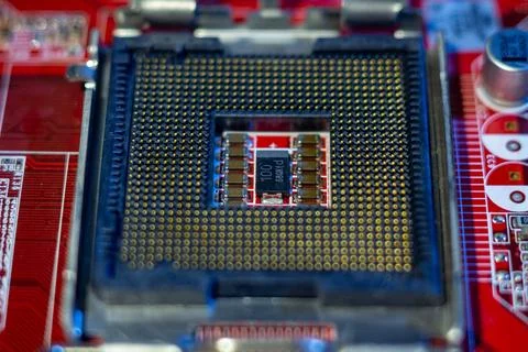 Empty cpu socket on red motherboard with electronic components and capacitors Stock Photos