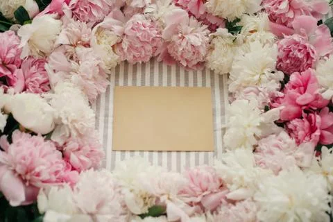 Empty craft card  in peonies frame flat lay on rustic table cloth. Space for  Stock Photos
