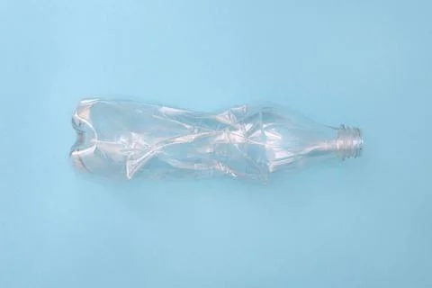 Empty crumpled plastic bottle on a blue background. Recycling concept. Ecology Stock Photos