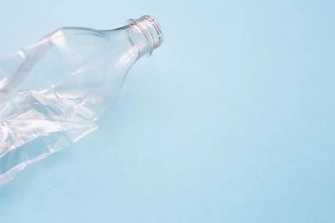 Empty crumpled plastic bottle on blue background with place for text. Copy space Stock Photos