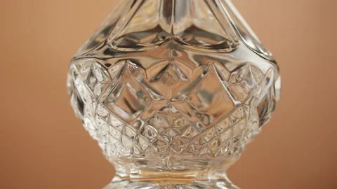 Empty crystal decanter close-up. Clear trancparent carafe rotating on orange Stock Footage 201944062