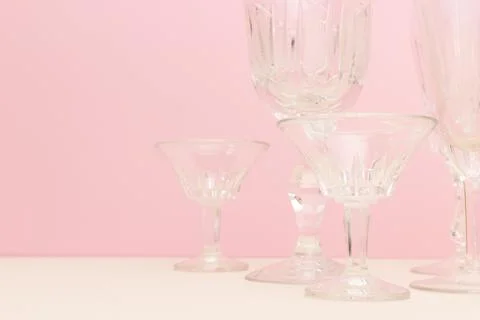 Empty crystal glasses in front of pink background. Stock Photos